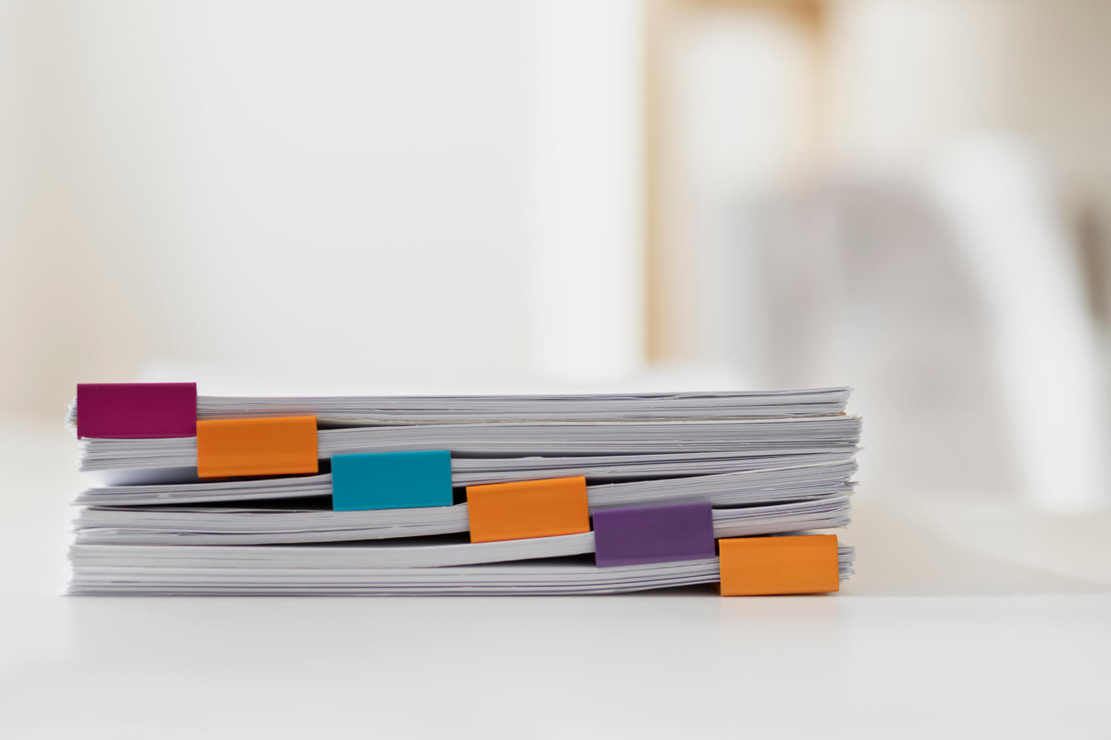 Pilha de documentos organizados com marcadores coloridos, representando o processo de construção e documentação de um Manual de Tom de Voz e estratégias de Branding