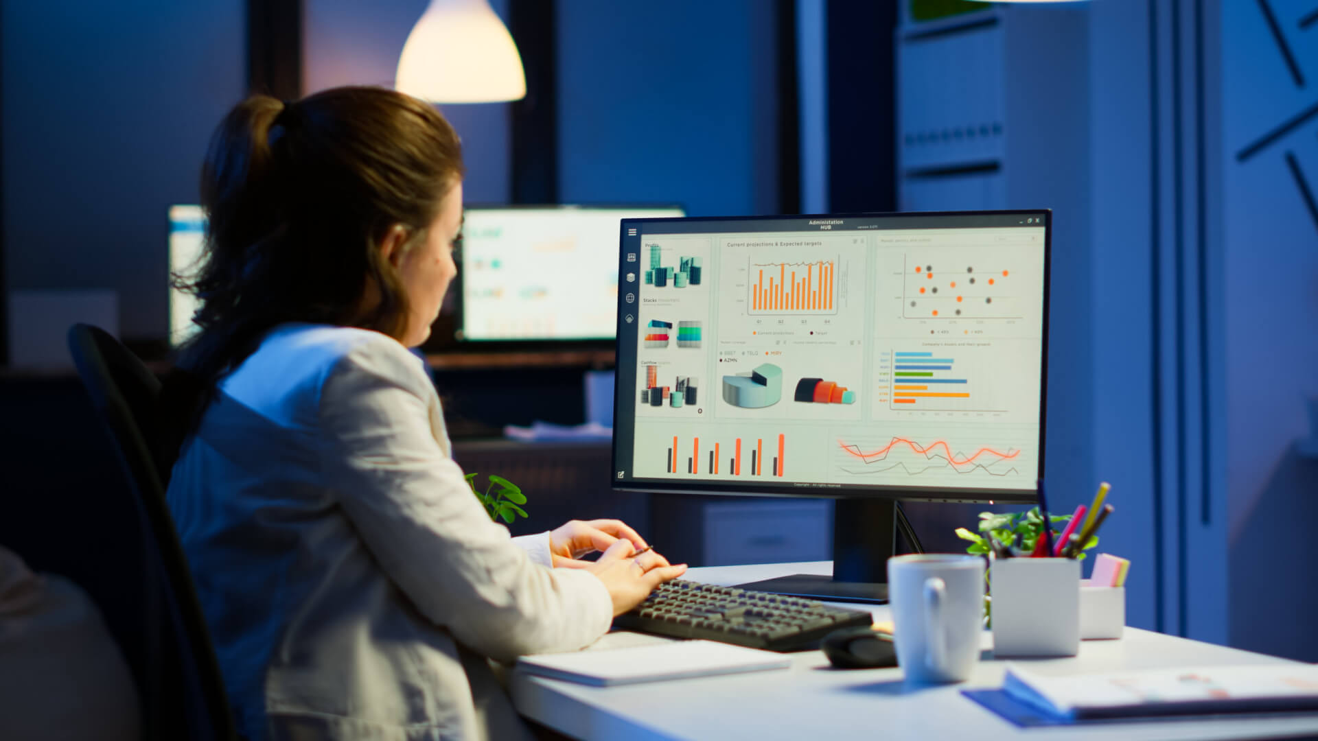 Profissional analisando dashboards com gráficos de desempenho e métricas no computador. Representa o uso de dados oriundos de UX Research e pesquisa com usuários para orientar decisões estratégicas de negócios.